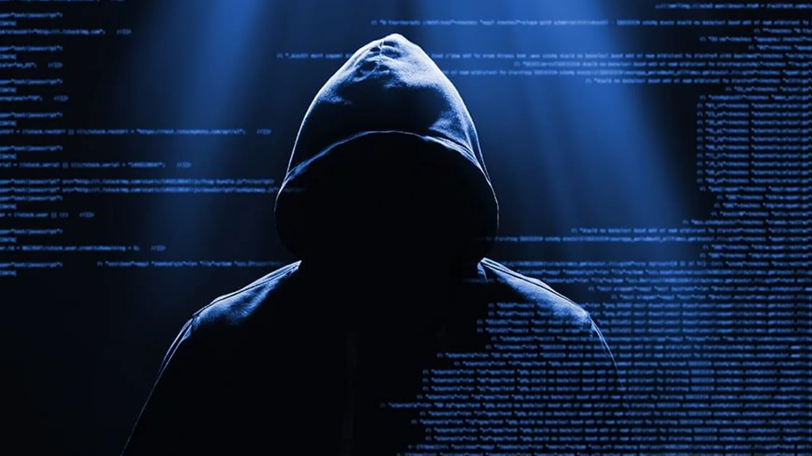 Silhouette encapuchonnée de dos, sans visage visible, devant un mur de code éclairé en bleu. L'image d'illustration type des articles sur le dark web.